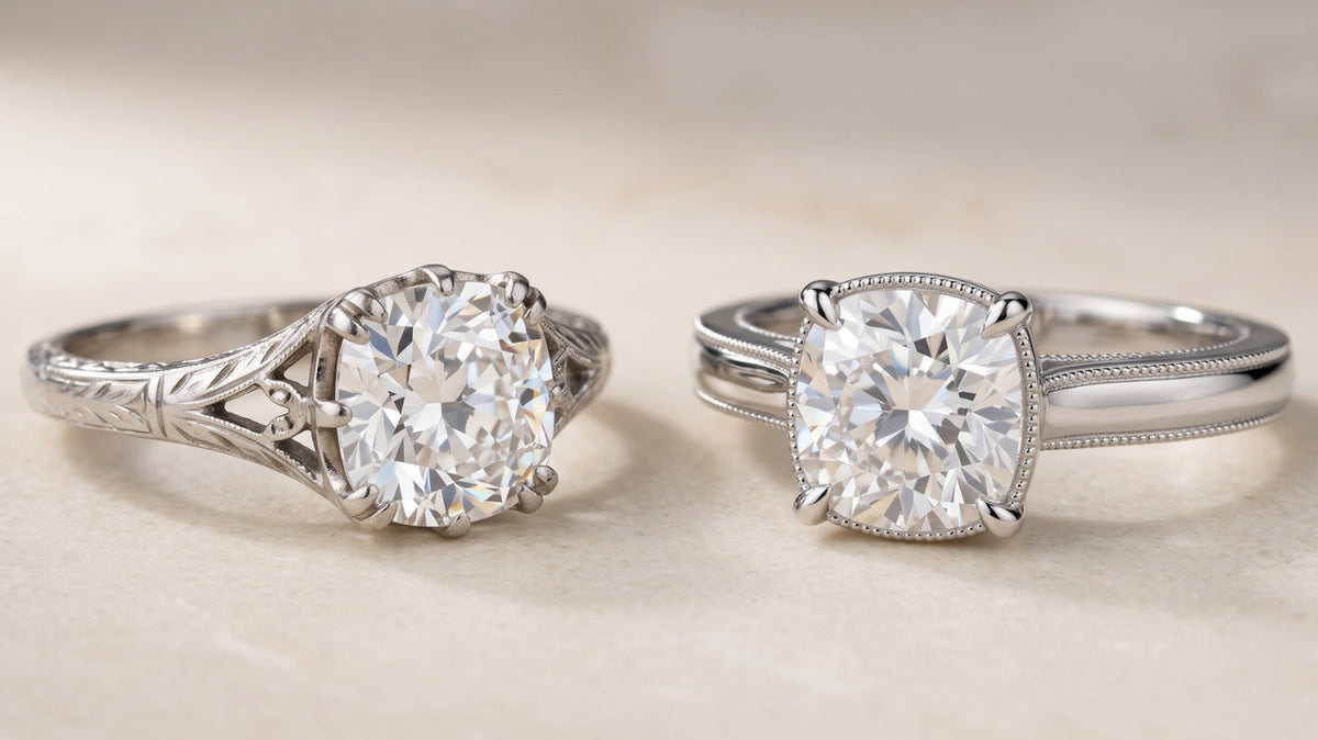 Two cushion-cut moissanite engagement rings sit side by side, contrasting a softly worn antique-style setting with a crisp newly made vintage-inspired design.